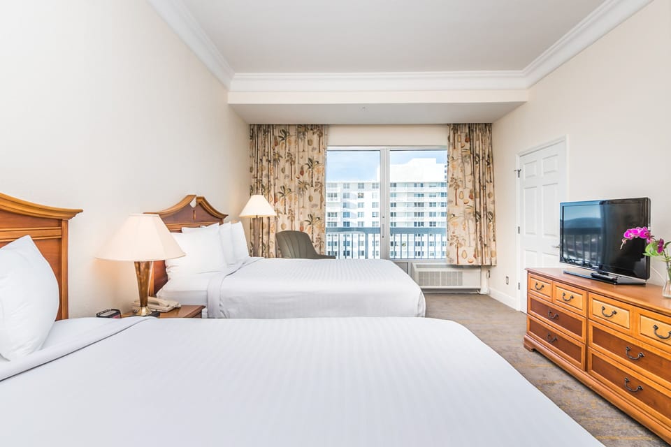 Relax in this spacious beach stay room featuring two plush queen beds, a flat-screen TV, and balcony access. Enjoy ocean breezes, natural light, and a cozy coastal vibe—perfect for unwinding after a day on the sand.