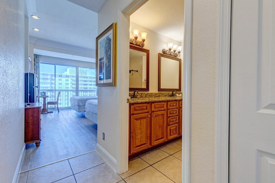 Inviting entryway leading to a spacious beachfront suite. Enjoy easy access to a double-sink vanity and a sunlit room with ocean-view balcony—perfect for a relaxing beach stay.