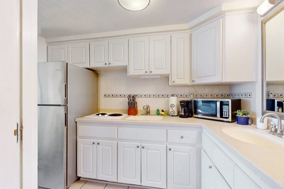 Clean, well-stocked kitchenette with full fridge, cooktop, microwave, and coffee maker—perfect for simple meal prep during your beach stay. A convenient space to refuel between oceanfront adventures.