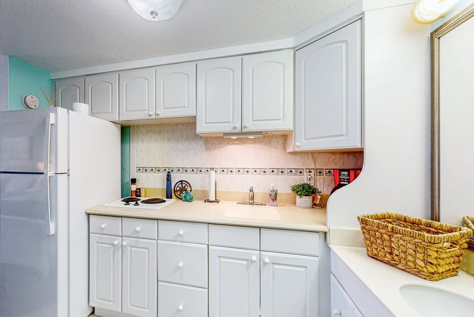 Cozy, fully equipped kitchenette perfect for easy beach-day meals. Features white cabinetry, cooktop, and fridge—an ideal setup for a relaxed oceanfront stay.