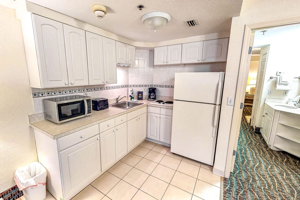 Enjoy the convenience of this bright beach stay kitchenette featuring a full fridge, microwave, toaster, cooktop, and ample storage—perfect for preparing simple meals after a day by the ocean.
