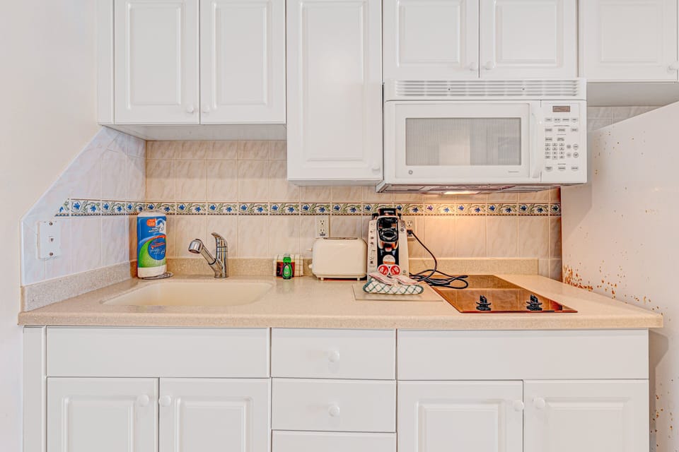 Convenient kitchenette equipped with cooktop, microwave, coffee maker, and sink—perfect for easy meals during your beach stay. Enjoy all the comforts of home while vacationing by the ocean.