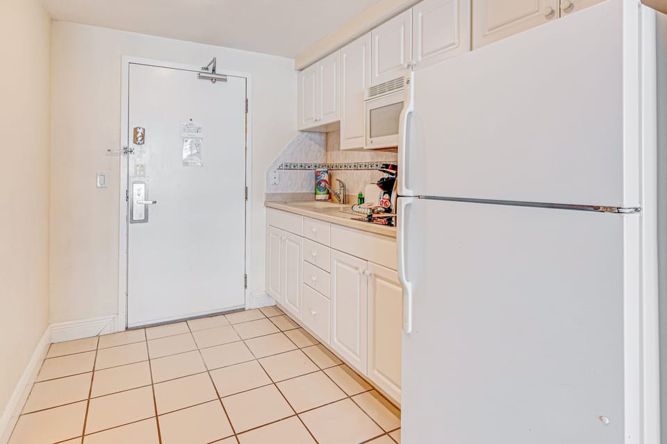 This bright kitchenette offers everything you need for a relaxed beach stay—full fridge, microwave, cooktop, and essentials—perfect for quick meals before heading out to the sand and surf.