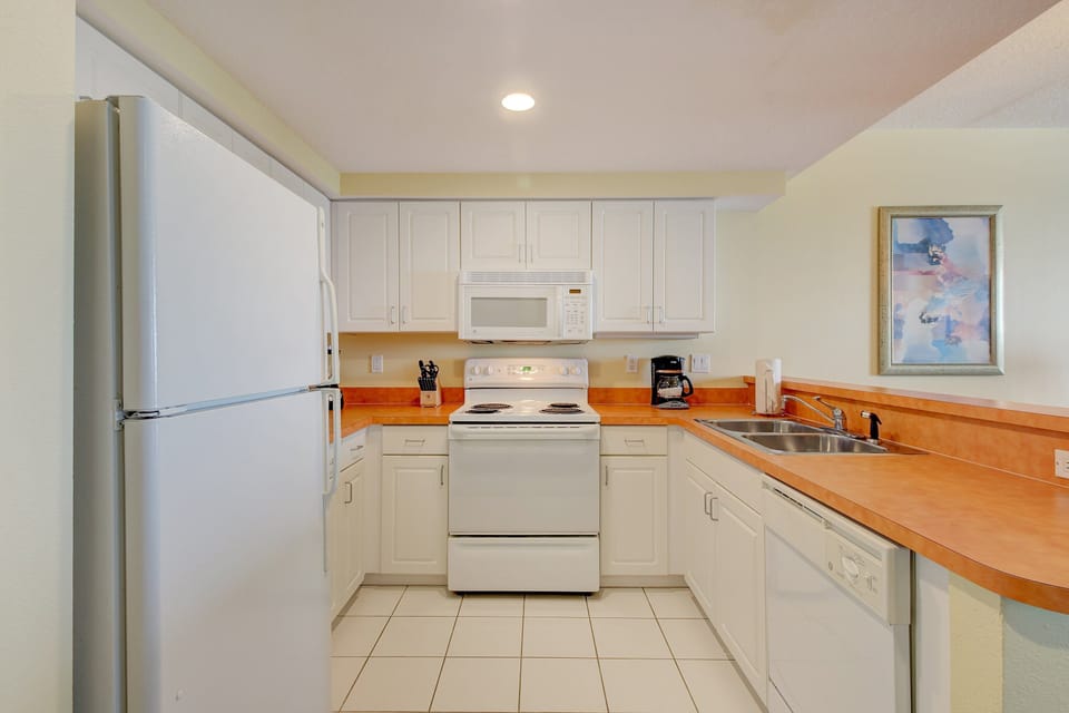 Spacious beach stay kitchen featuring crisp white cabinets, full appliances, and ample counter space—perfect for preparing seaside meals before heading back out to the shore.