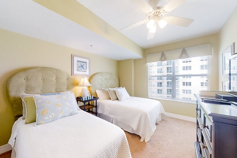 Bright and airy twin bedroom with soft beach-themed décor and plenty of natural light. A peaceful space perfect for unwinding after a fun-filled beach stay.