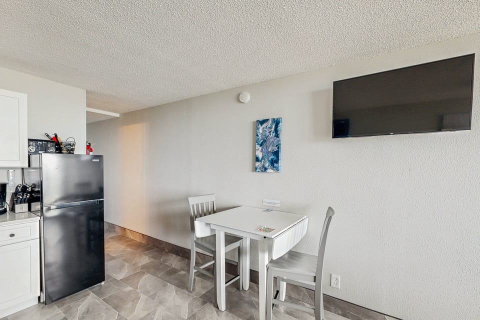 Enjoy meals during your beach stay at this cozy dining nook with kitchenette and wall-mounted TV. Ideal for relaxing after a day at the beach, offering convenience, comfort, and easy coastal living.