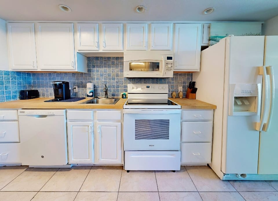 Spacious coastal kitchen with full-size appliances, ample cabinetry, and beach-inspired finishes. Ideal for a relaxing beach stay, offering everything you need to prepare meals before or after a fun-filled day by the ocean.