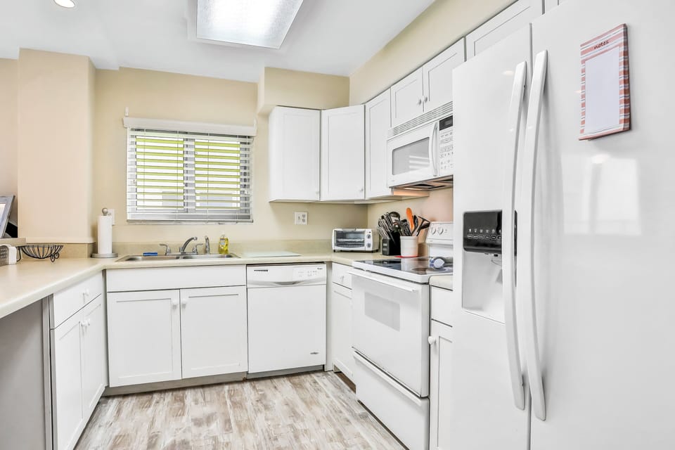 Fully equipped kitchen with bright cabinetry and modern appliances, perfect for preparing meals during your beach stay. Enjoy convenience and comfort just steps from the shoreline.