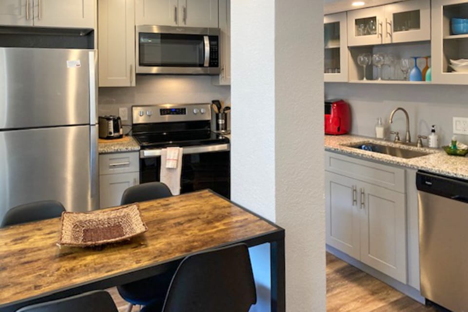 Stylish coastal kitchen with stainless steel appliances, granite countertops, and a cozy dining nook. Perfect for preparing meals during your beach stay and enjoying easy, comfortable vacation living near the shore.