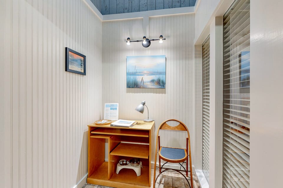 Charming beach-inspired nook featuring a small desk, chair, and coastal artwork—perfect for catching up on emails or planning your next adventure during a relaxing beach stay getaway.