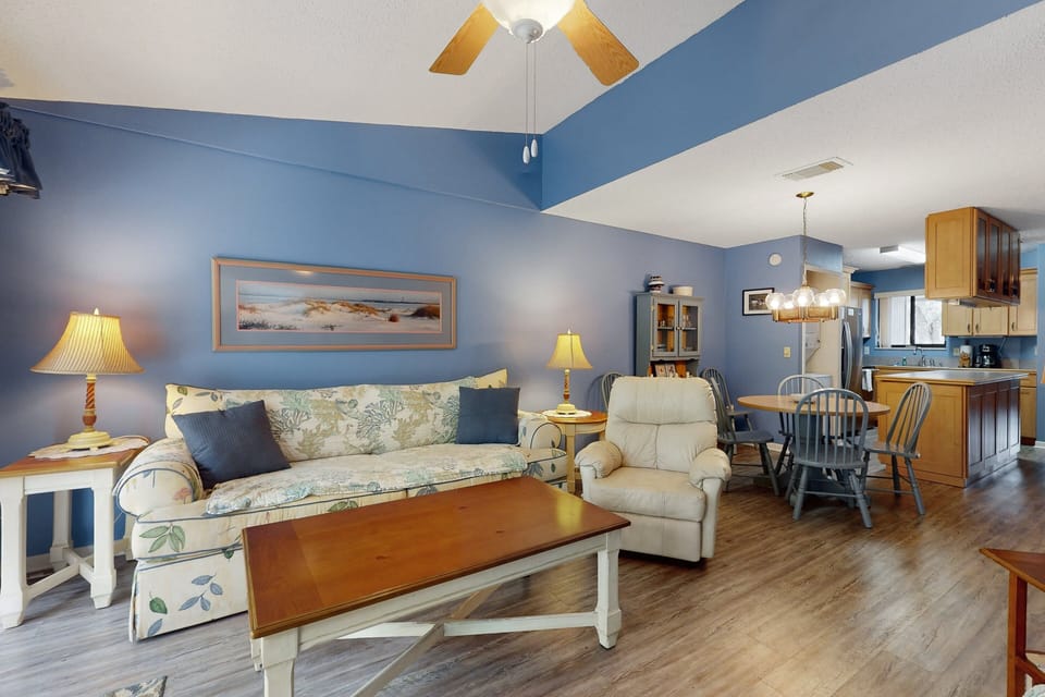 Relax in this open-concept living space with comfortable seating, vaulted ceilings, and seamless flow to the dining area and kitchen—ideal for unwinding after a sun-filled day during your perfect beach stay getaway.
