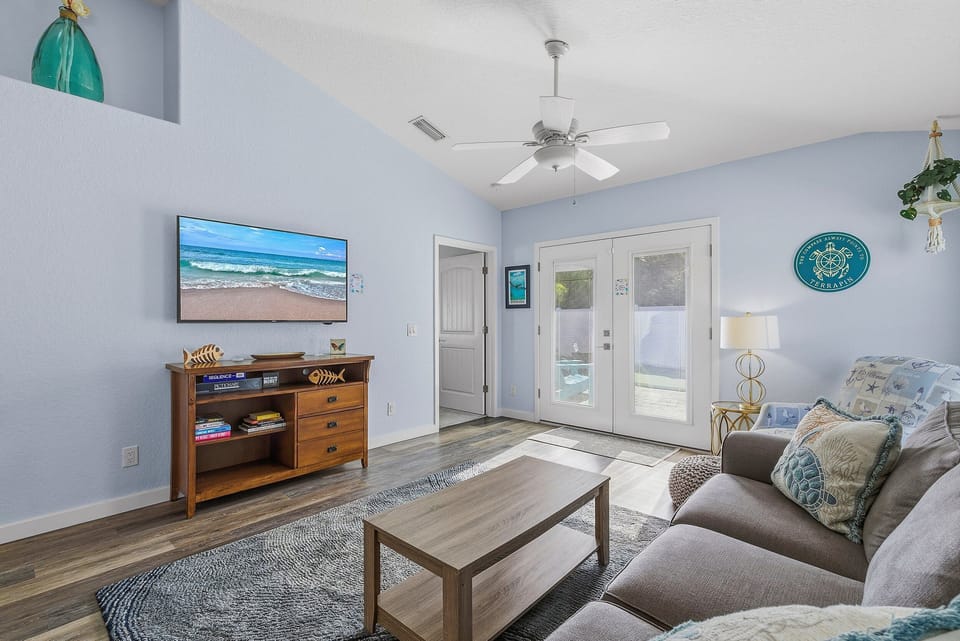 Airy coastal living room featuring beach-inspired décor, comfy seating, and plenty of natural light. The perfect space to unwind after a day at the beach during your relaxing seaside vacation stay.