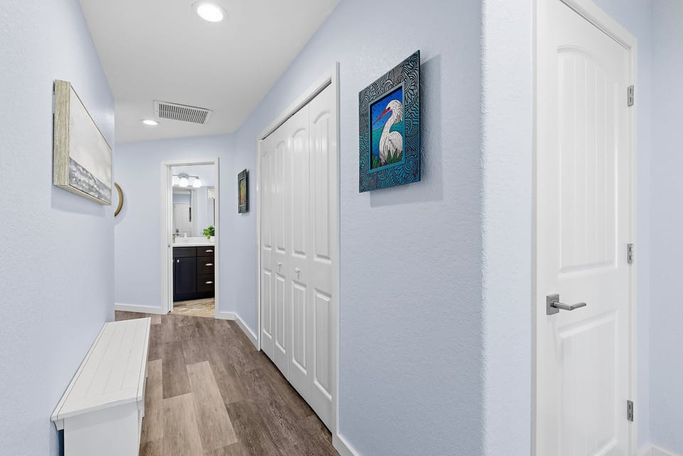 Light and airy hallway featuring beach-inspired artwork, clean lines, and coastal charm. A welcoming transition space that complements your relaxing beach stay vacation experience.