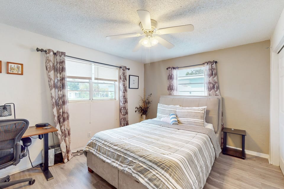 Rest comfortably in this bright beach stay bedroom featuring a cozy bed, natural light, and a convenient workspace. Calm tones and a relaxing atmosphere create the perfect retreat after a day enjoying the beach.