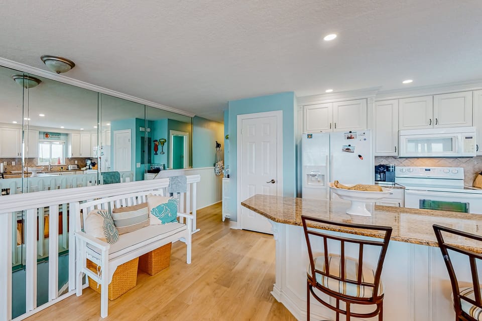 Enjoy this airy coastal kitchen and comfy seating nook—perfect for relaxing after a sun-filled beach stay. Bright décor, ample counter space, and inviting accents create a welcoming space for your ocean getaway.