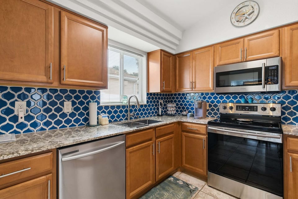 Enjoy cooking during your beach stay in this bright coastal kitchen featuring modern appliances, ample counter space, and ocean-inspired tile accents—ideal for preparing meals after a day at the beach.