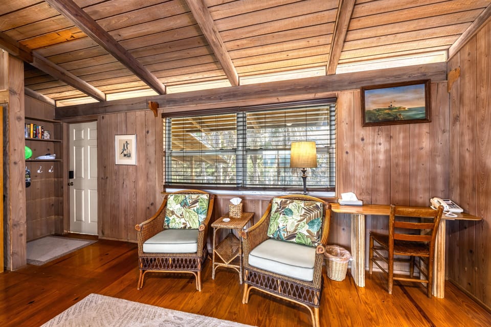 A tranquil retreat, with a desk and seating illuminated by sunlight and soft coastal tones.