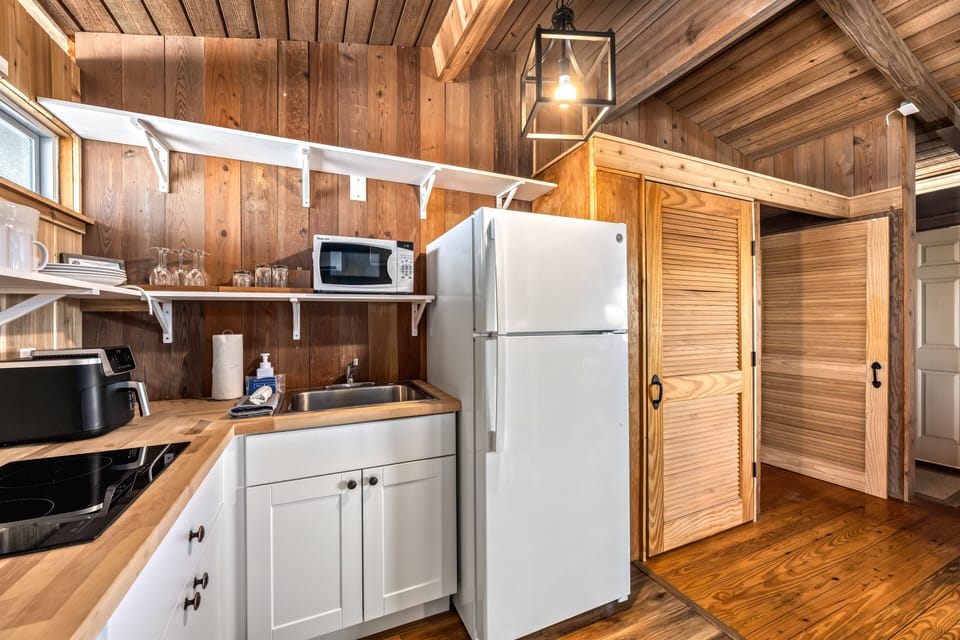 The full kitchen is stocked and ready for meal prep or casual drinks with ocean scenery nearby.