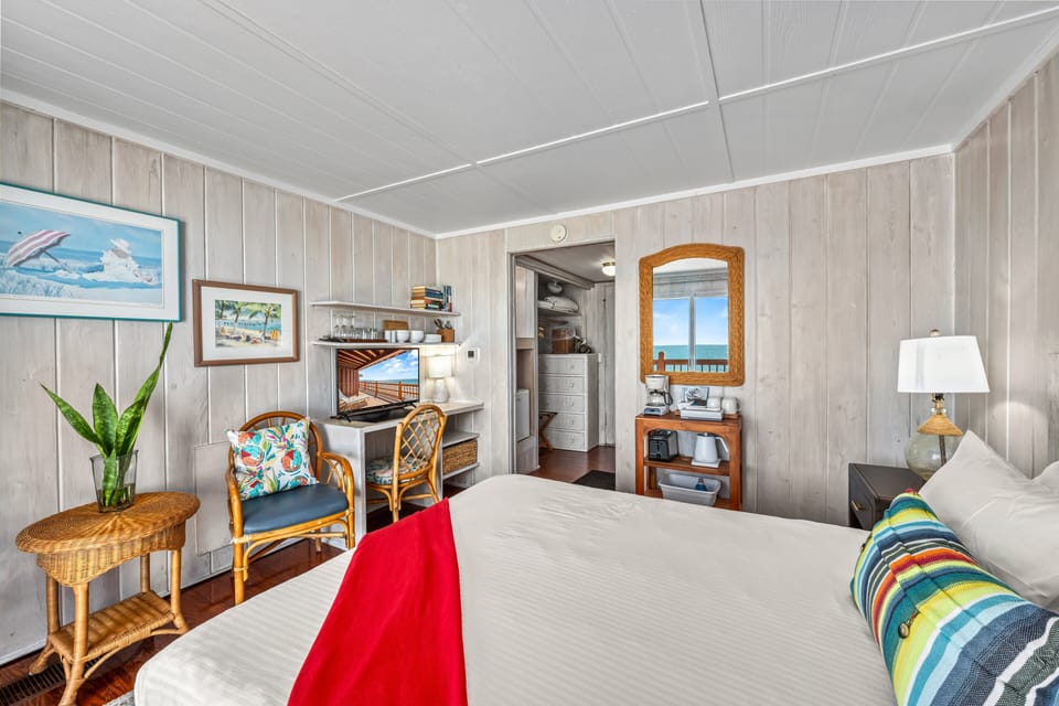 The queen bed anchors the room, with a nearby desk and chairs offering a quiet spot for work or reading.