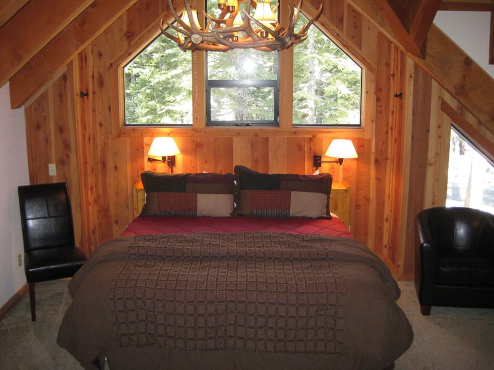 The beautifully designed bedroom features cozy bedding and large windows that offer stunning views of the surrounding forests, ensuring a restful retreat.