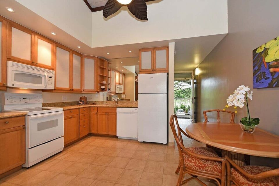 Enjoy home-cooked meals in a well-equipped kitchen with warm wood cabinetry, full appliances, and a charming dining setup under soft lighting.