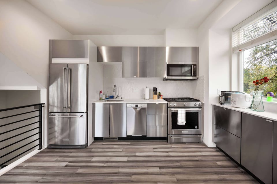 The generous countertops, contemporary cabinetry, and large window inviting natural light create a bright and welcoming space, perfect for preparing meals while enjoying the peaceful views of the surrounding greenery. 