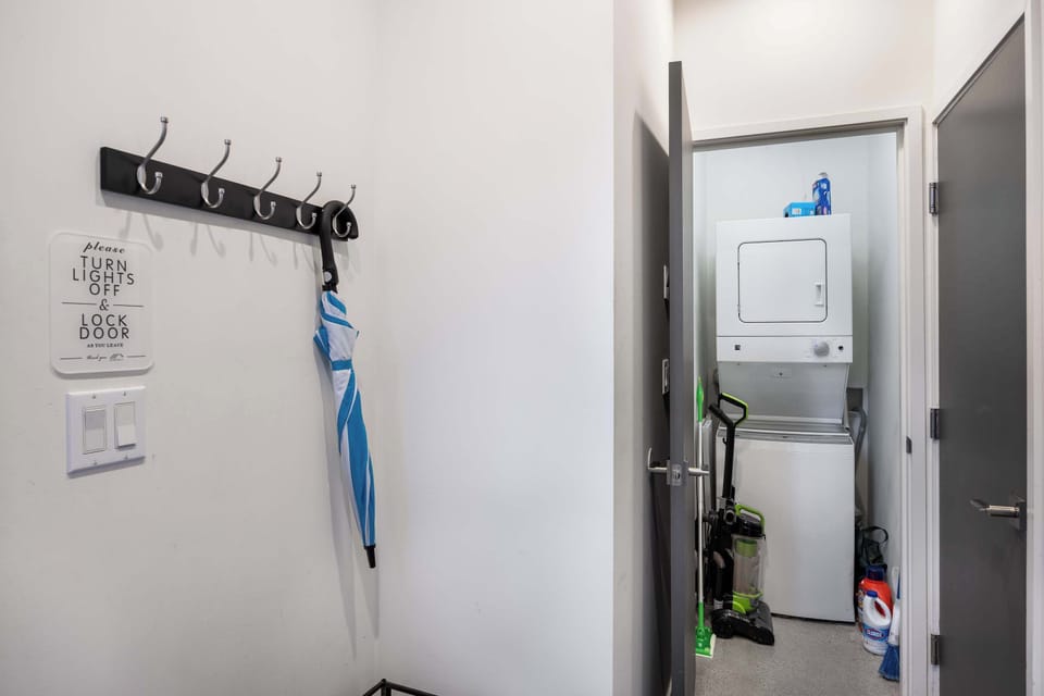 Convenient entryway with coat hooks and an umbrella stand, leading to an in-unit laundry room equipped with a washer and dryer. Perfect for keeping your stay organized and comfortable, with all the essentials right at your fingertips.