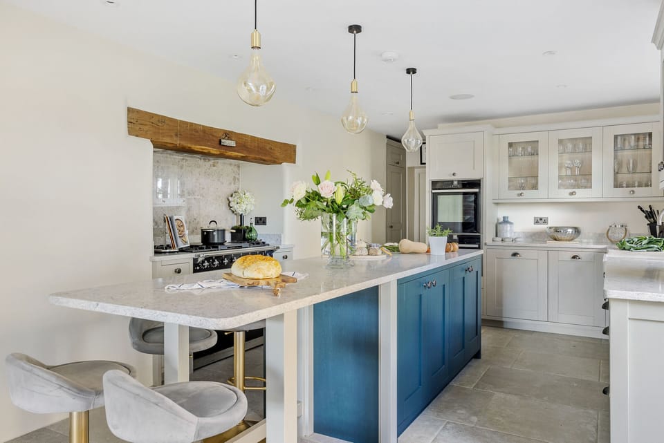 Large kitchen with blue island and marble top.