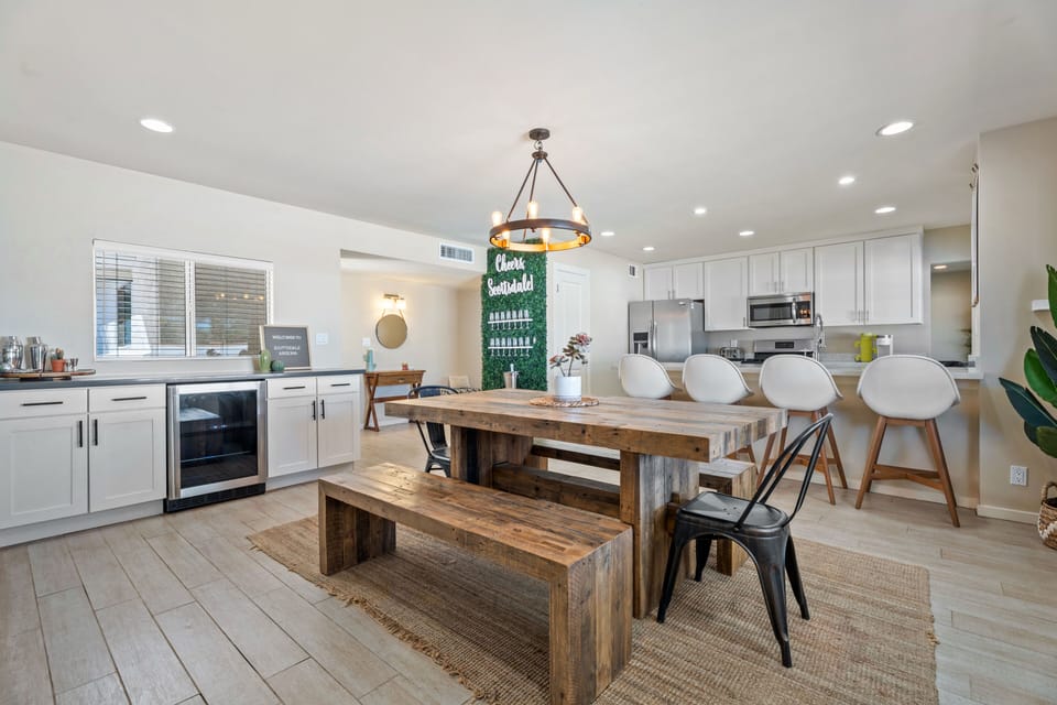 Dining area adjacent to the kitchen, featuring a wooden table, bench seating, and a beverage cooler.