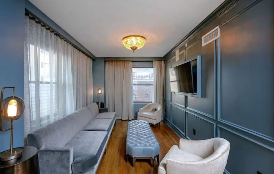 Unwind on the plush sofa beneath elegant chandelier glow.