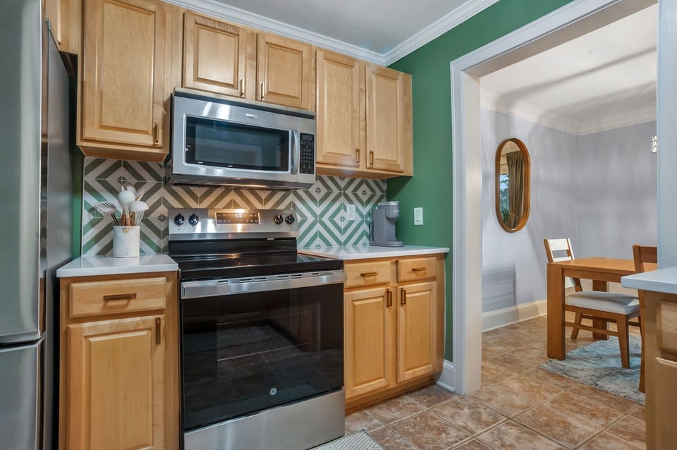 Your fully equipped kitchen features modern appliances and stylish green geometric tile backsplash, perfect for preparing meals during your stay.