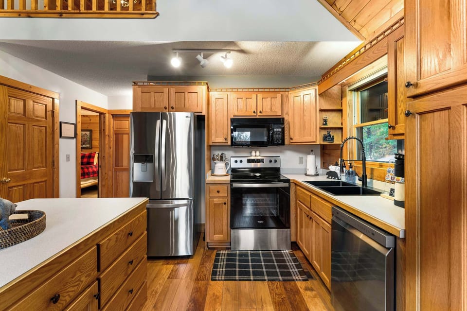 Modern, full kitchen: fridge, dishwasher, stove, and coffee maker.