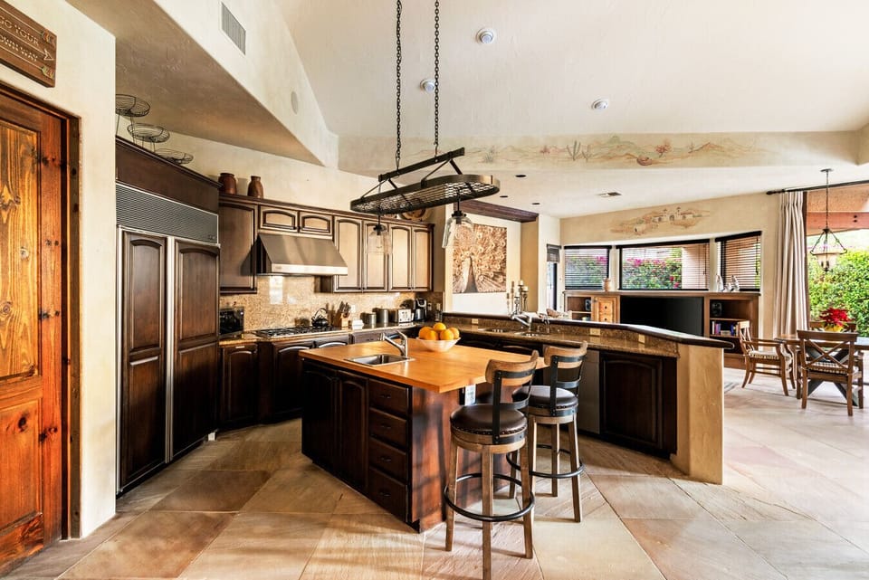A chef-inspired kitchen featuring rich wood cabinetry, premium appliances, and a central island with seating. Thoughtfully designed for both everyday cooking and entertaining, it opens seamlessly to the living and dining areas.