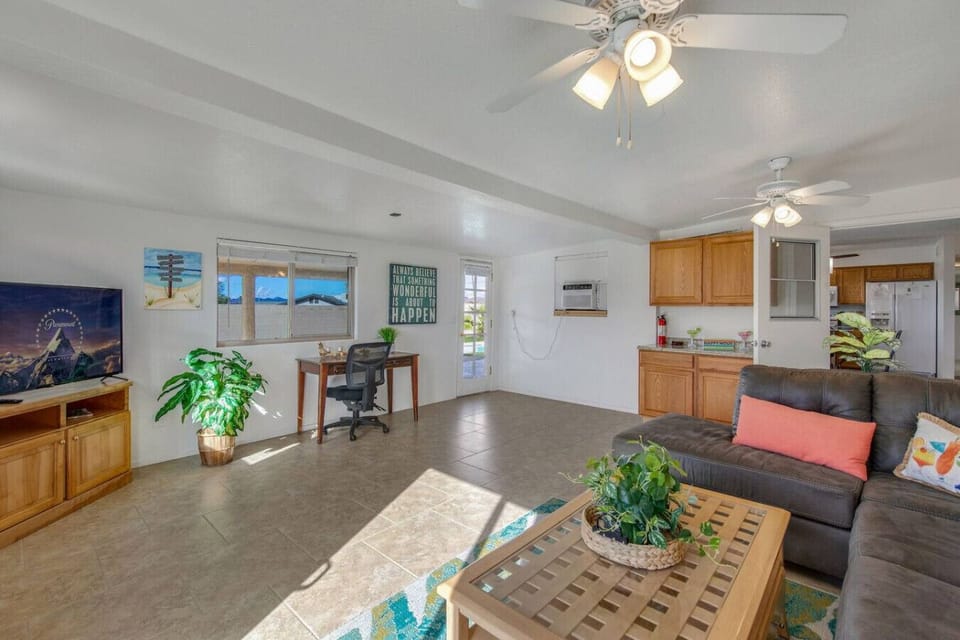 Bright living space with ceiling fans and a dedicated workspace—ideal for remote work.