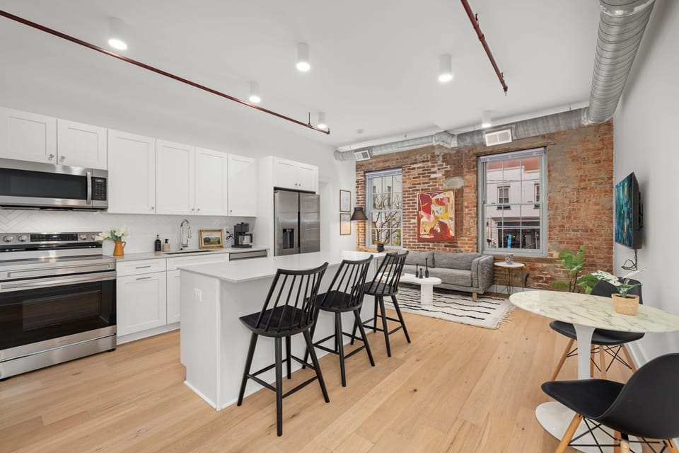 Open-concept living with exposed brick, modern kitchen, island seating