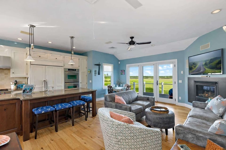 Open living room and kitchen on upper level, combining cozy seating and coastal decor with glimpses of Chipmans Cove.