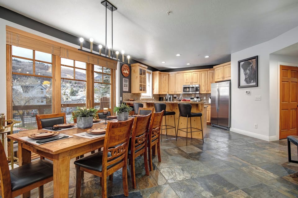 Spacious open-concept kitchen and dining area with warm wood cabinetry, modern appliances, and a welcoming breakfast bar.