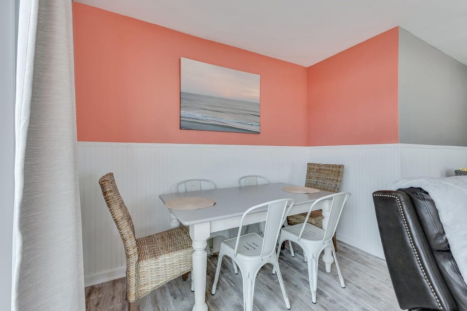 Gather around your charming dining table for memorable meals beneath the cheerful coral accent wall and coastal artwork.