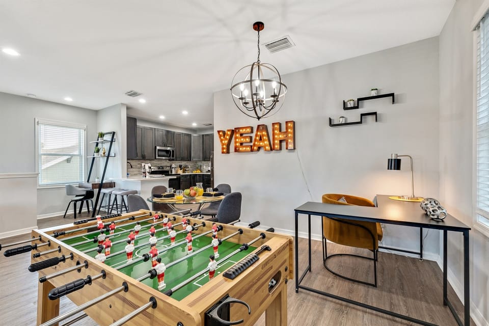 A fun and stylish dining/game space featuring a foosball table, modern décor, and a bold illuminated “YEAH” sign for an upbeat vibe.