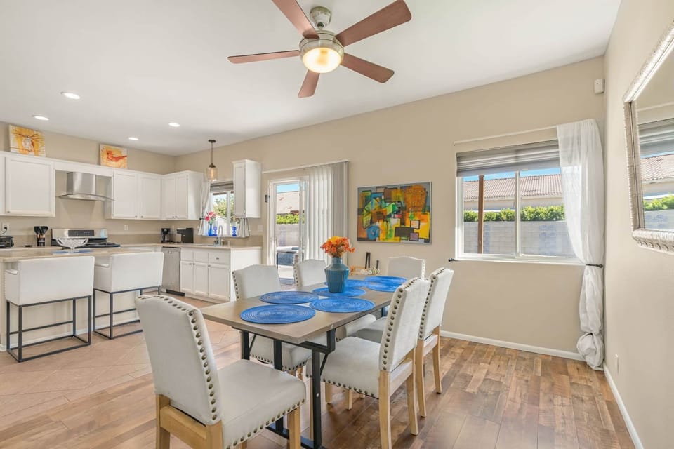 An eight-seat dining table with colorful décor sits beside large windows & sliding doors