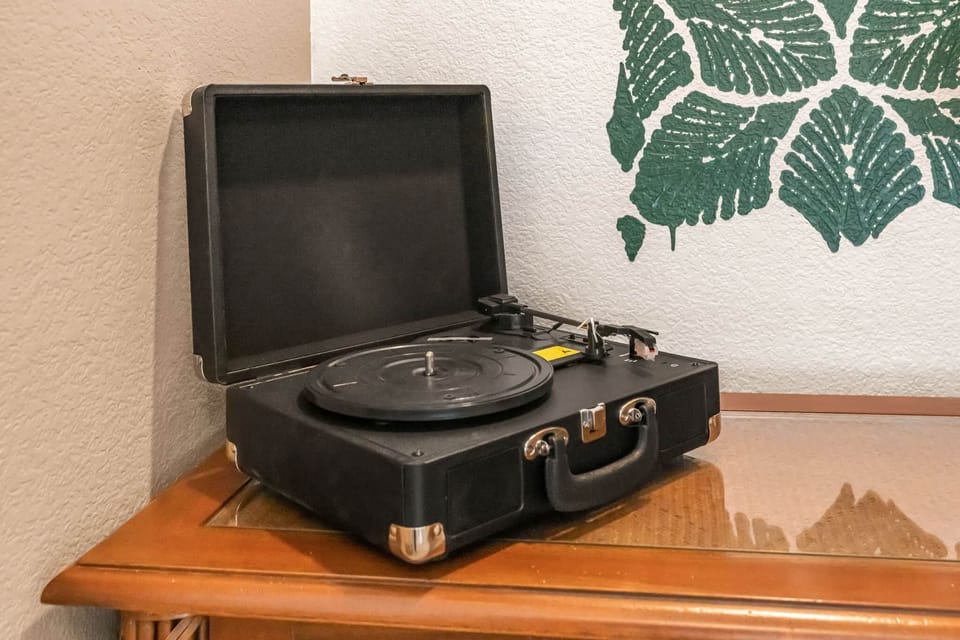 Classic take on a modern portable record player, displayed on wooden furniture & custom art behind