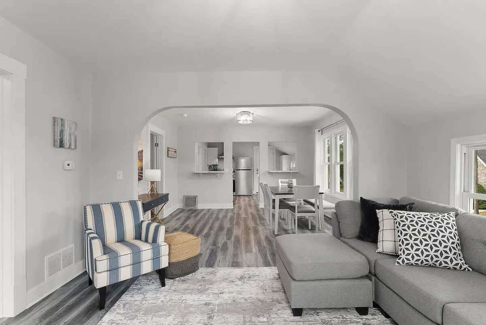 Living room features a couch and chair along with a smart tv. It's open to the dining area that seats 6. 