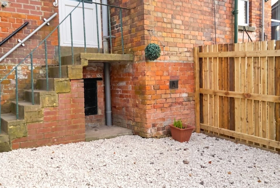 Private fenced rear garden with gravel courtyard and steps to the entrance.