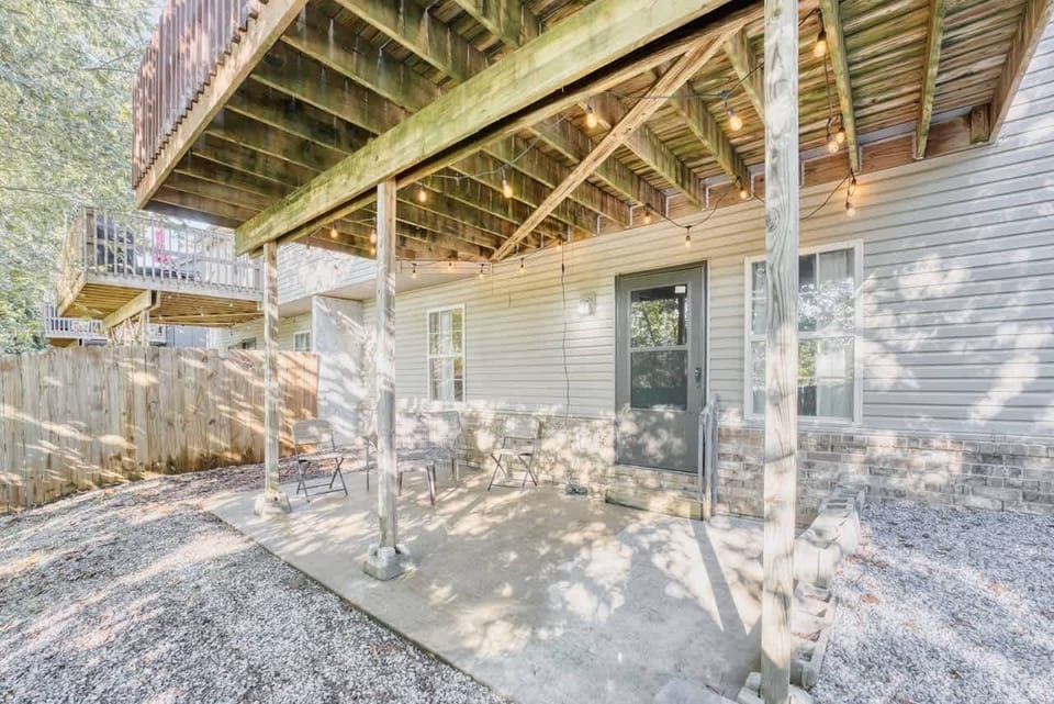 Escape to the shaded lower patio with seating and twinkling lights—perfect for morning coffee or evening cocktails surrounded by trees.