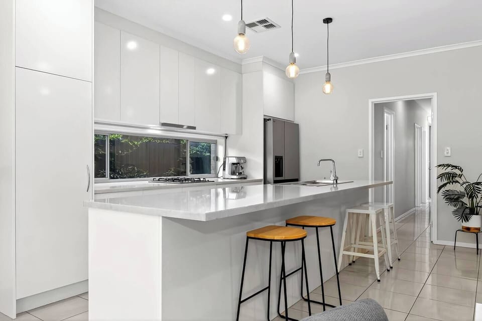 The kitchen offers an inviting place to cook, with a generous island and modern appliances—gas cooktop, oven, fridge, dishwasher and espresso machine—making meal preparation simple and enjoyable.