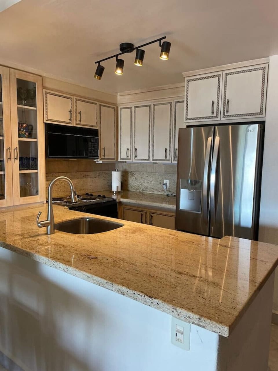 Fully equipped kitchen with granite countertops, stainless steel appliances, and charming cream-colored cabinetry.