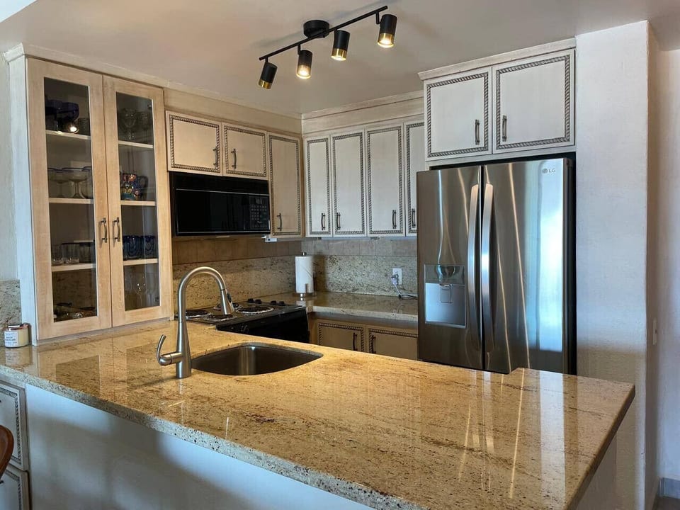Fully equipped kitchen with granite countertops, stainless steel appliances, and charming cream-colored cabinetry.