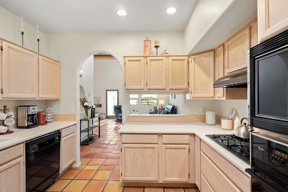 Your fully equipped kitchen features warm wood cabinetry, modern appliances, and charming terracotta tile flooring, perfect for preparing meals during your stay.