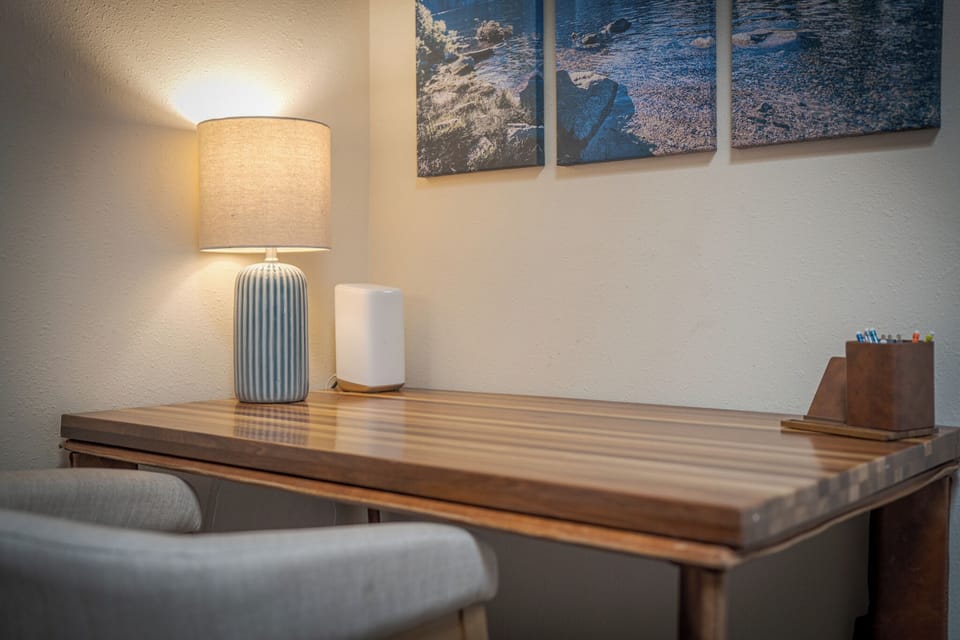 Your dedicated workspace features a beautifully crafted wooden desk with modern lighting and coastal artwork, perfect for catching up on work or planning your adventures.