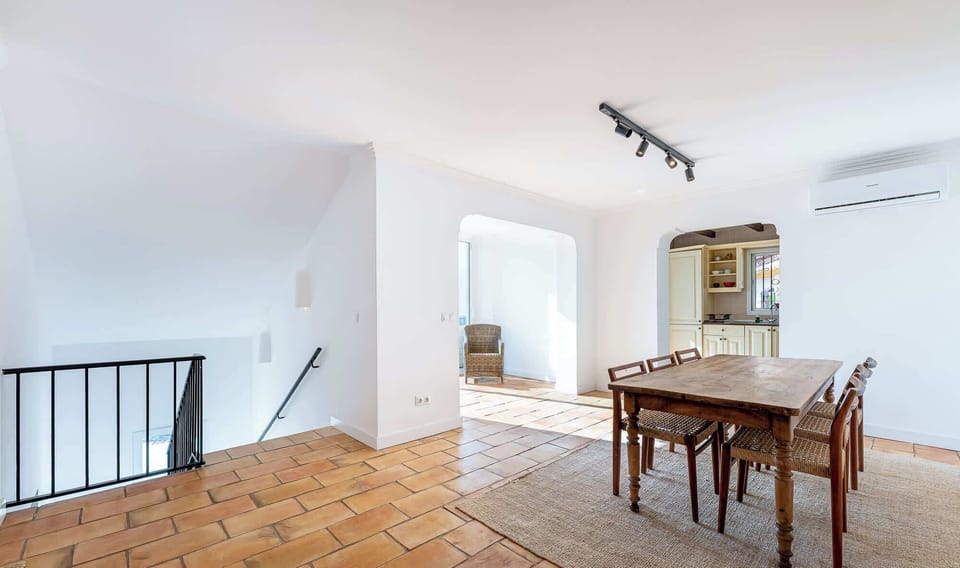 Spacious dining area with terracotta floors, wooden table for six, arched doorways, and bright natural light. Rustic charm blends with modern comfort in this inviting home layout.